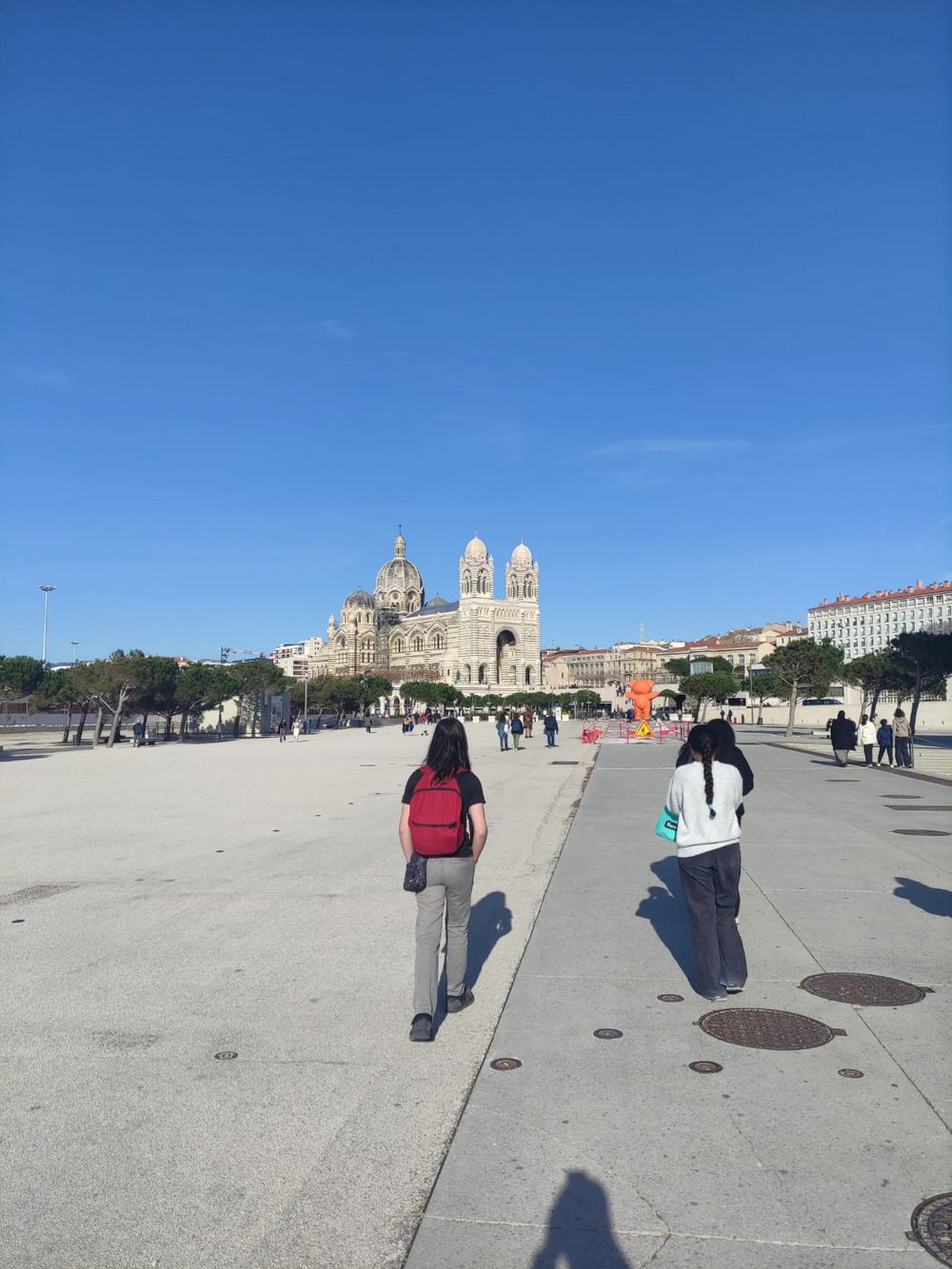 Les jeunes marchent dans Marseille, on peut y voir au loin Cathédrale Sainte Marie Majeure de Marseille
